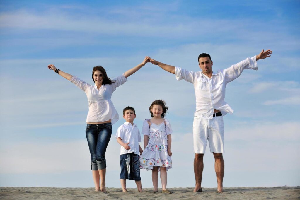 family on beach showing home sign Stock Free