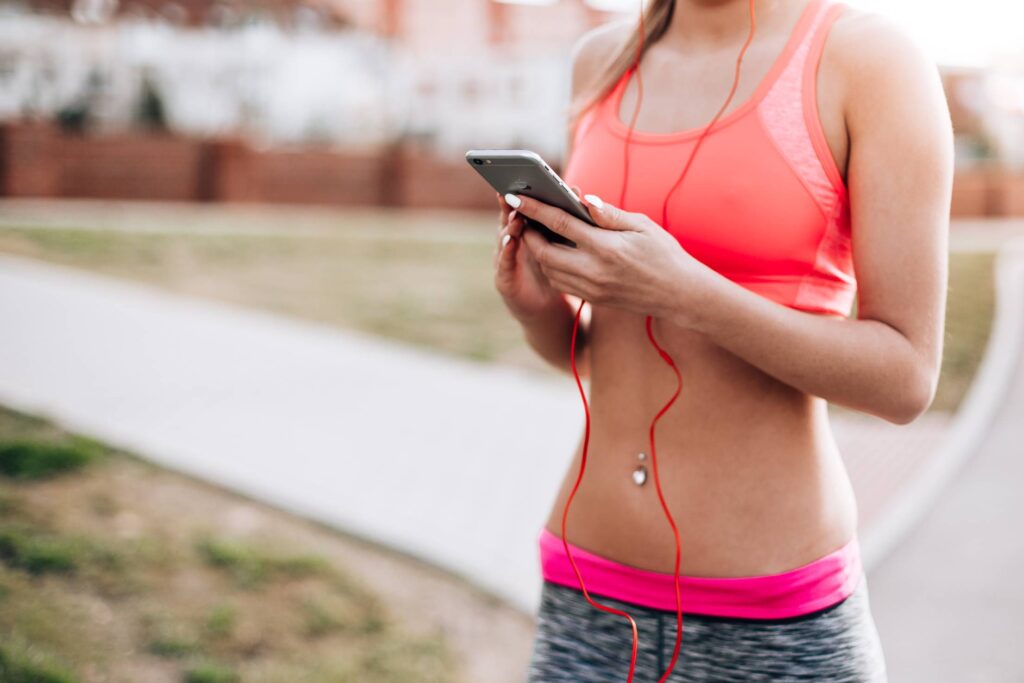 Fitness Girl Listening to Streaming Music on Her Phone Free Photo