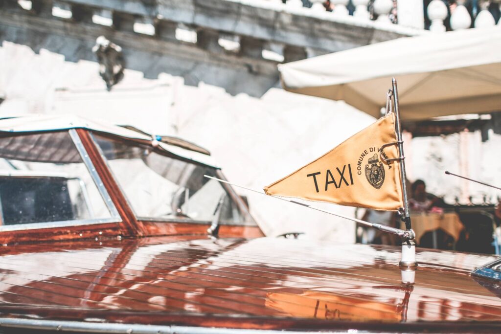 Flag on Iconic Boat Taxi in Venice, Italy Free Photo