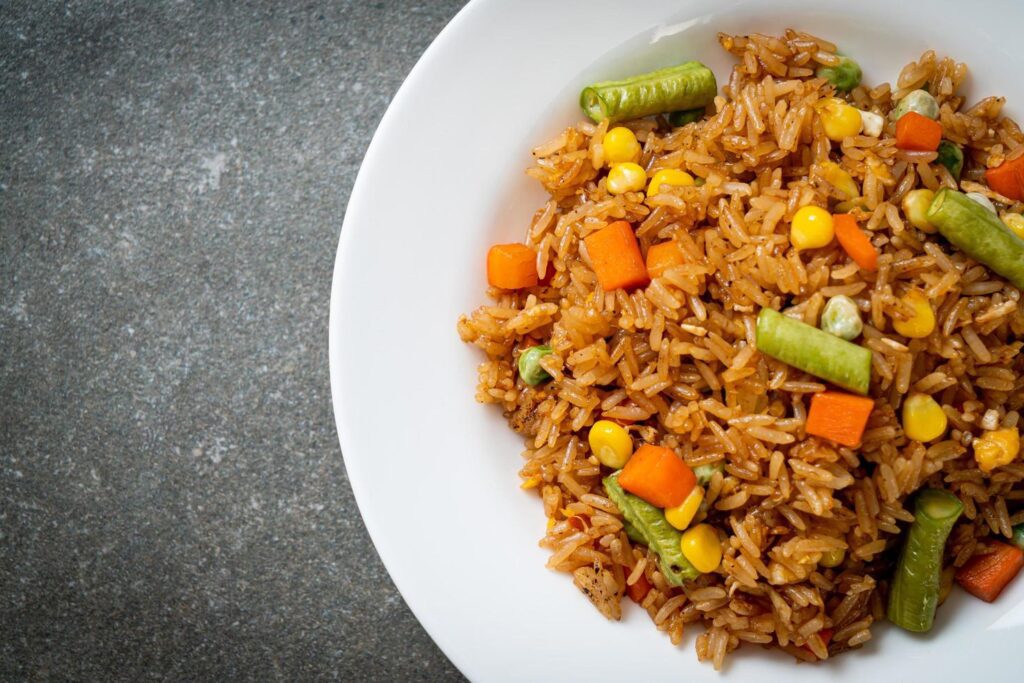 Fried rice with green peas, carrots, and corn – vegetarian and healthy food style Stock Free