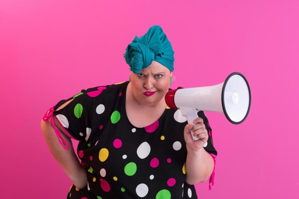 Funny plus size woman woman girl posing isolated on pastel pink wall background studio portrait. People sincere emotions lifestyle concept. Mock up copy space. Screaming in megaphone. Stock Free