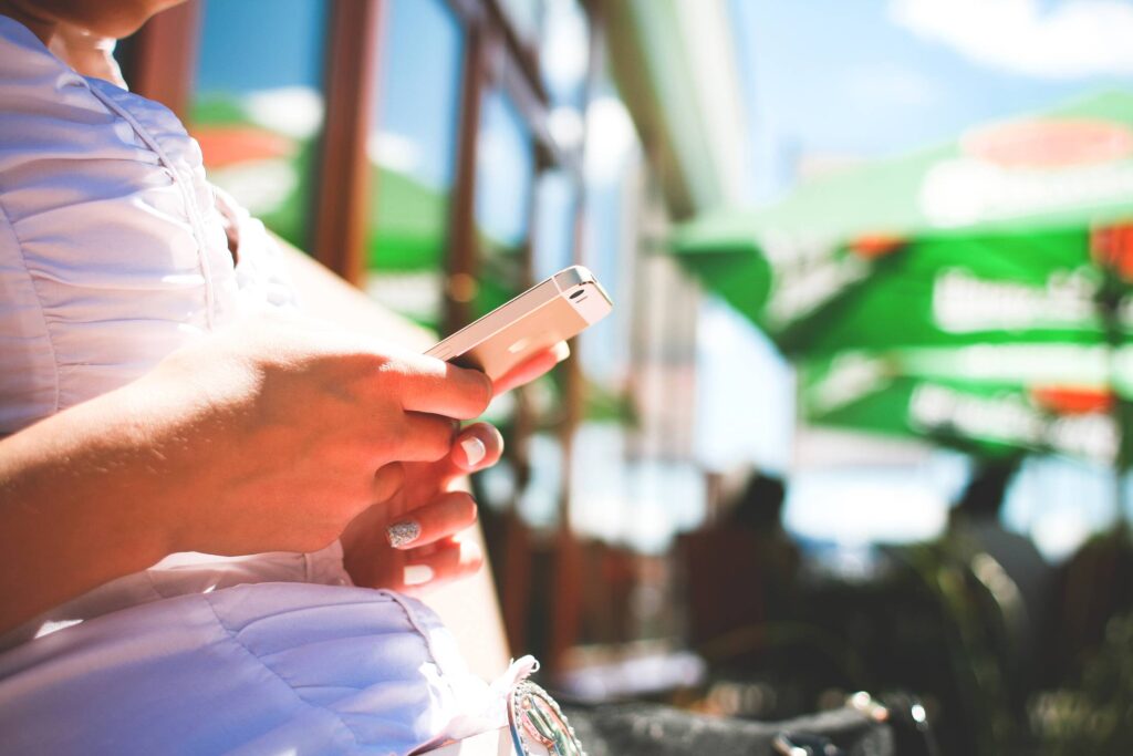 Girl Is Typing On Her iPhone In Caffe Free Photo