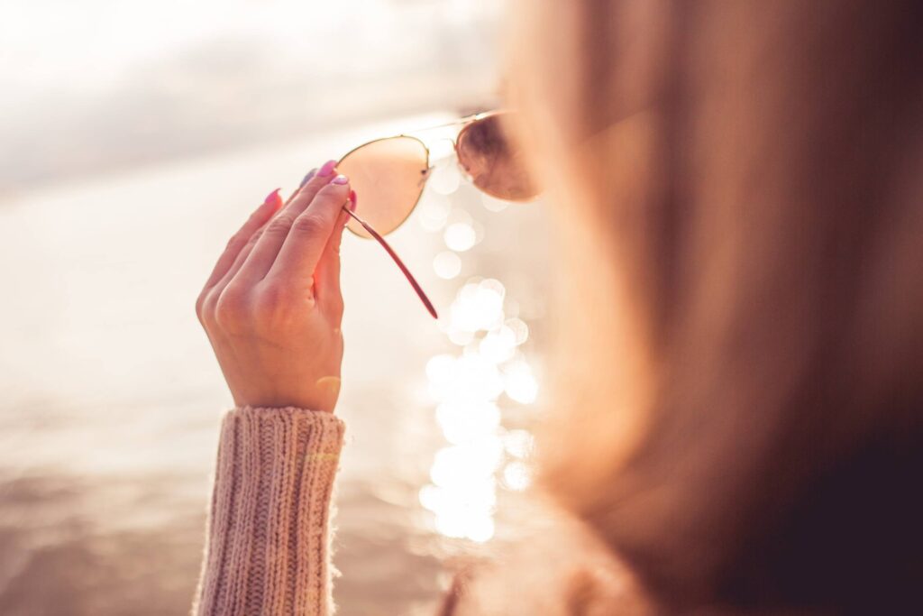 Girl Looking at the Sea Through Sunglasses Free Photo