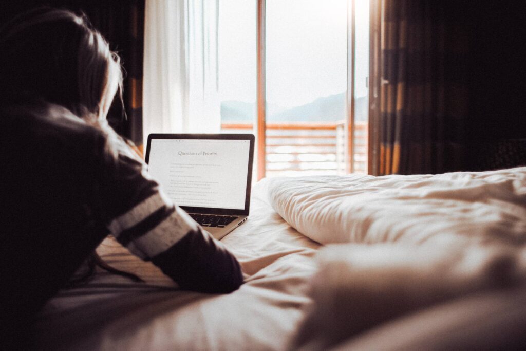 Girl Reading a Blog in a Bedroom Free Photo