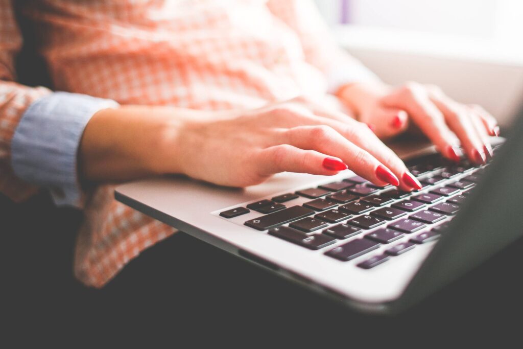 Girl Typing on her MacBook Pro Close Up Free Photo