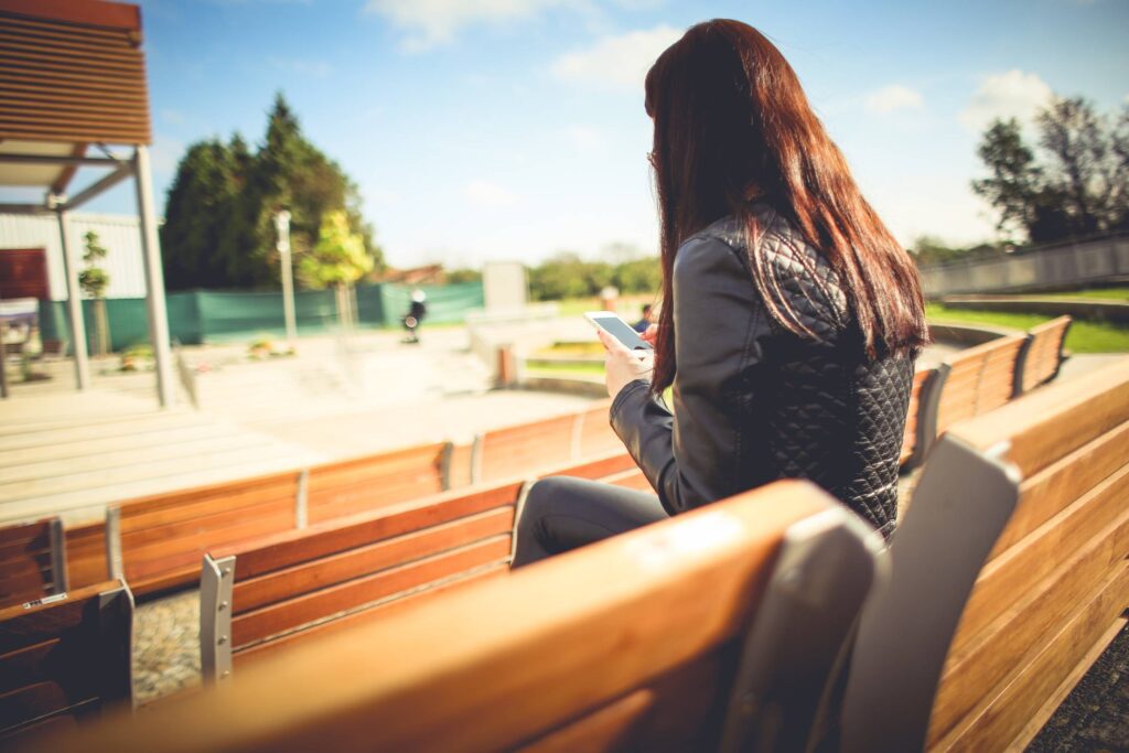 Girl Using her iPhone Outside Free Photo