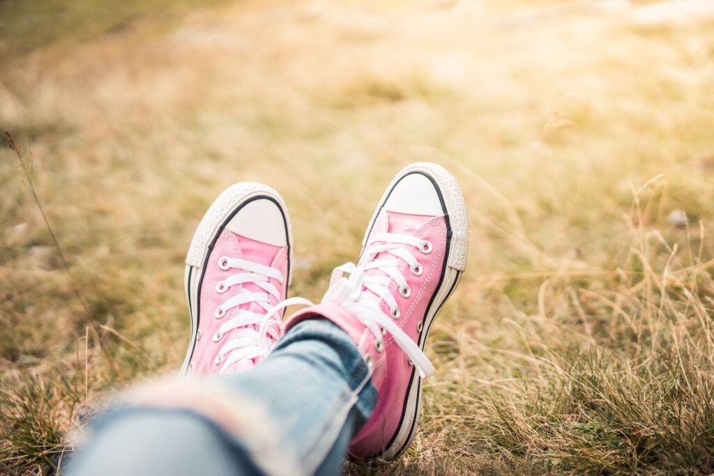 Girl With Pink Shoes Laying in Meadow Free Photo