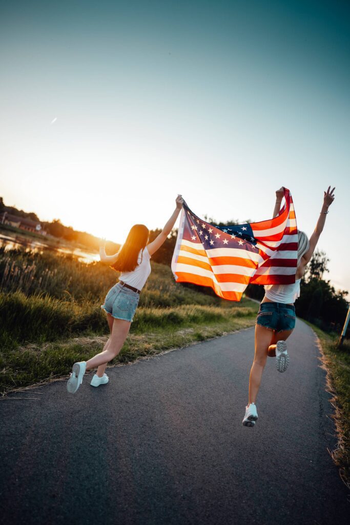 Girls Dancing with an American Flag Free Photo