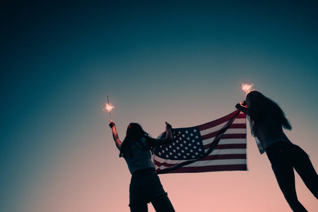 Girls Holding American Flag and Sparklers in The Early Evening Free Photo