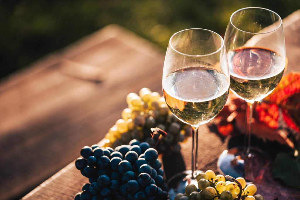 Glasses of White Wine on a Wooden Table with Grapes Free Photo