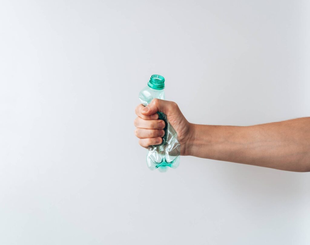 Hand Holding a Crumpled Plastic Bottle Free Photo