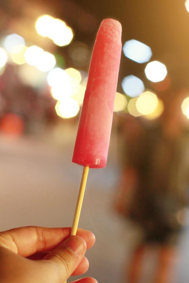 Hand holding Thai homemade Ice cream or ice freezer pop in bokeh light at night market and street food Stock Free