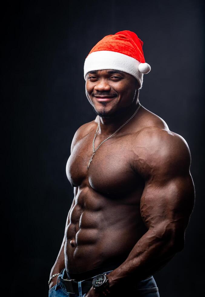 Handsome attractive fit santa on dark background. Shirtless muscular man with funny christmas hat. Stock Free