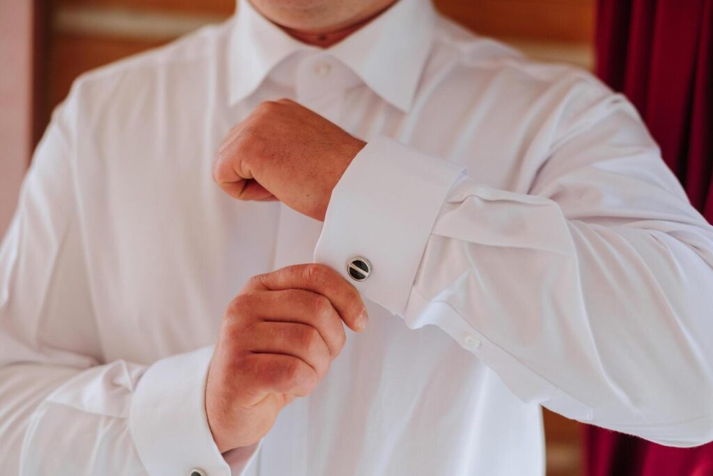 handsome business man buttoning shirt sleeves at home. The groom is preparing for the wedding. Close-up photo. Stock Free