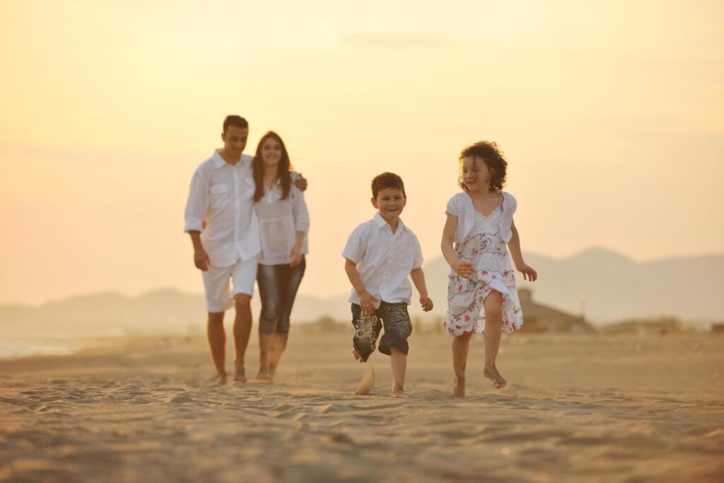 happy young family have fun on beach at sunset Stock Free