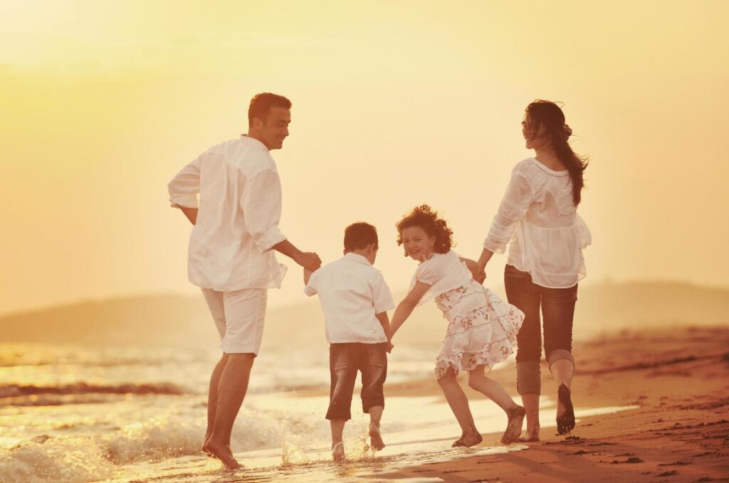 happy young family have fun on beach at sunset Free Photo