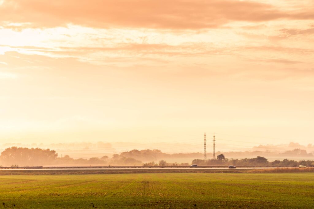 Highway Road with Cars and Electricity Pylons Foggy Golden Hour Free Photo