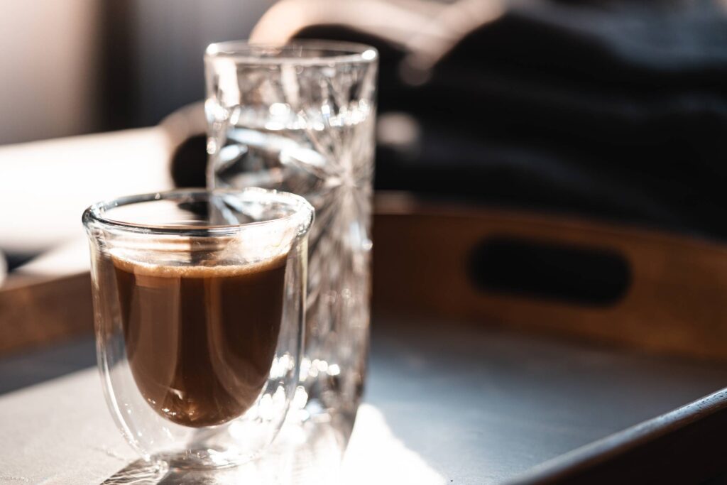 Homemade Lungo Coffee and a Glass of Water on a Tray Free Photo