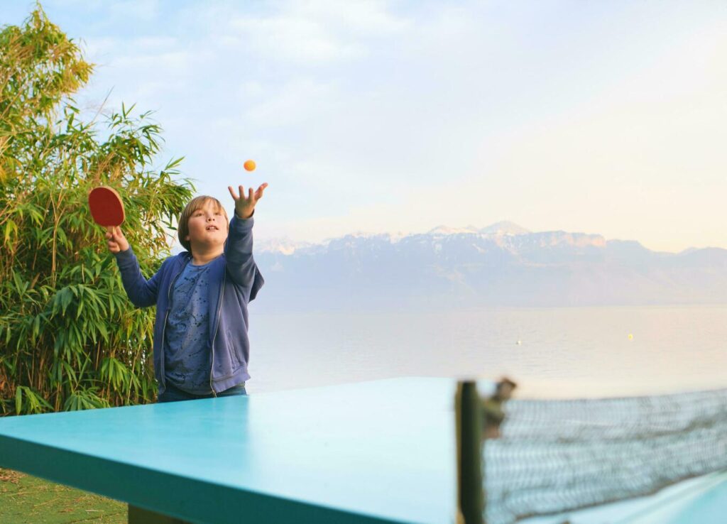 Kid boy playing ping pong by the lake, active lifestyle for children Stock Free