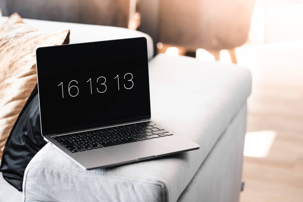 Laptop with a Clock Screensaver on a Sofa Free Photo