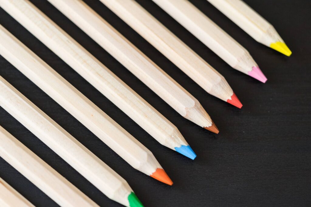 Long Colored Pencils in a Row on Black Desk Free Photo