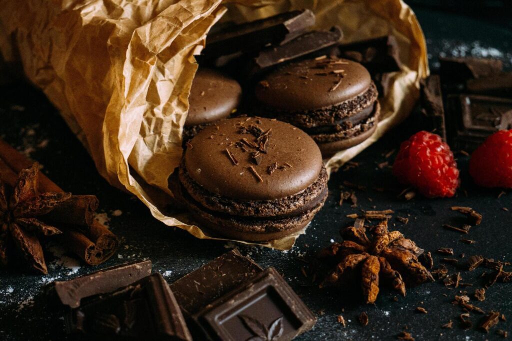 Macaroons with berries, chocolate and badiane on a black background Stock Free