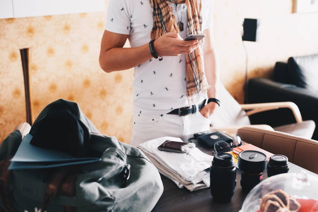 Man Checking His Phone while Packing for a Trip Free Photo