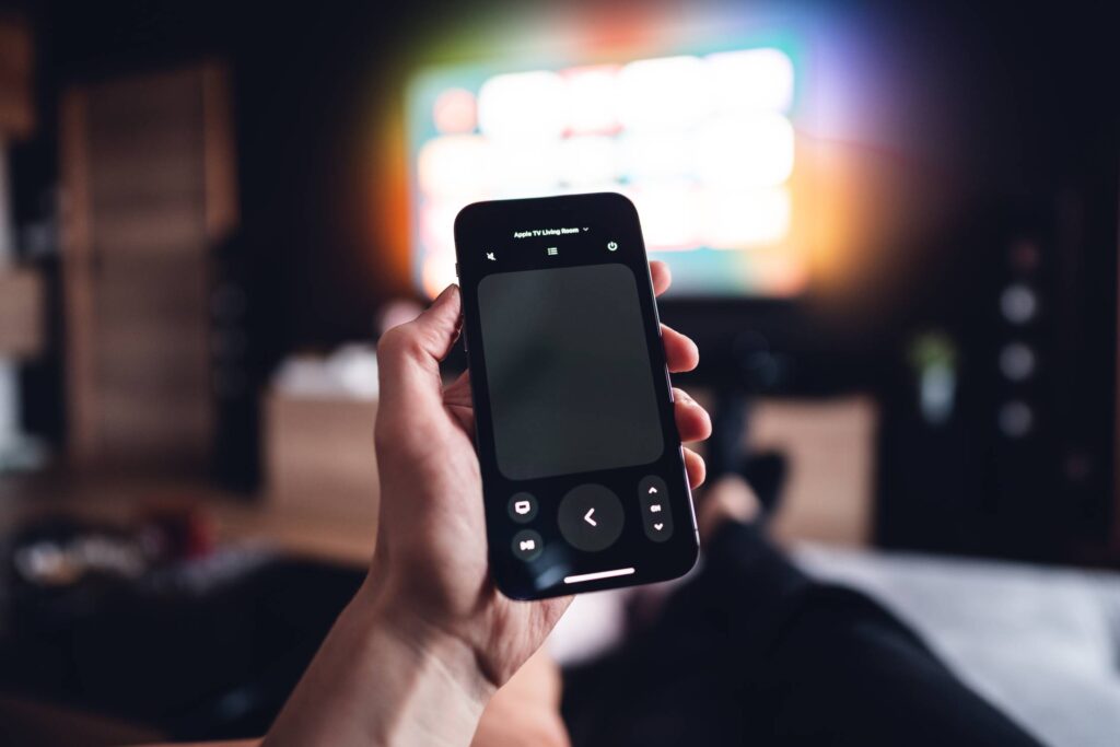 Man Controlling Apple TV via iPhone Remote Free Photo