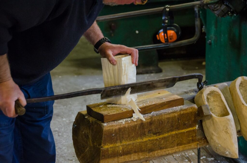 Man cutting wood for a clog Stock Free