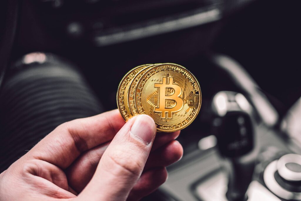 Man Holding a Bitcoin Coin in a Car Free Photo