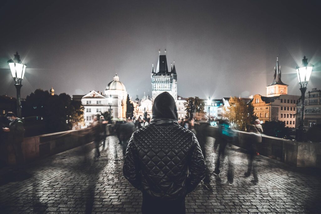 Man in a Hoodie Standing Still Against Crowds on Charles Bridge, Prague Free Photo