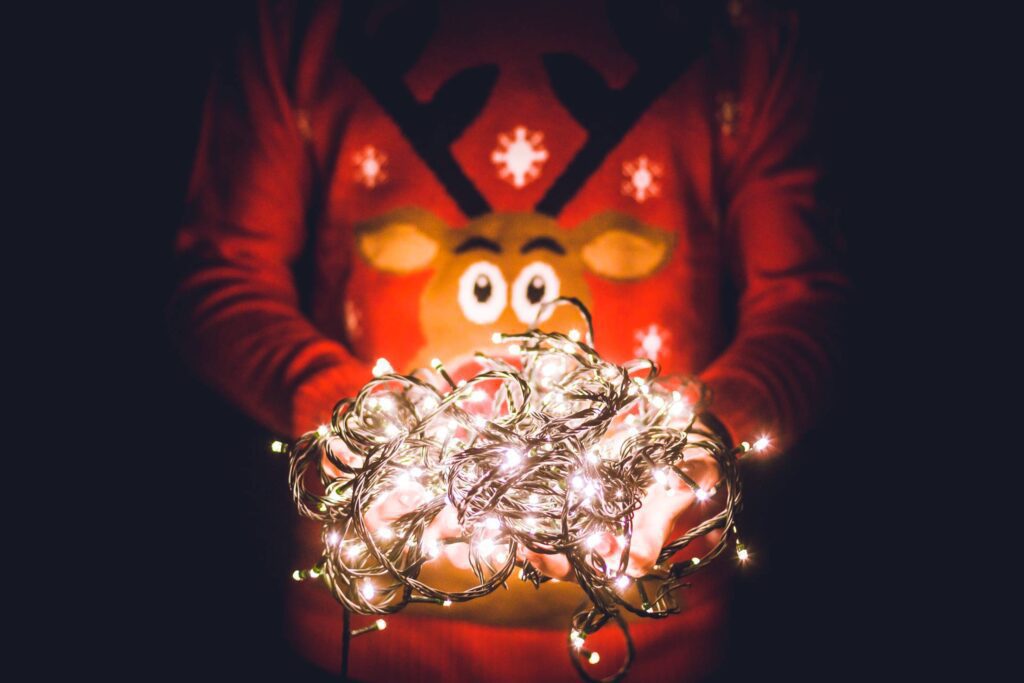 Man in Christmas Sweater Holding Christmas Lights Free Photo