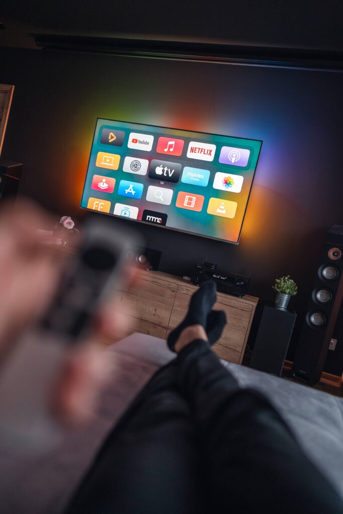 Man is Lying on a Sofa and Watching Movies on Apple TV Free Photo