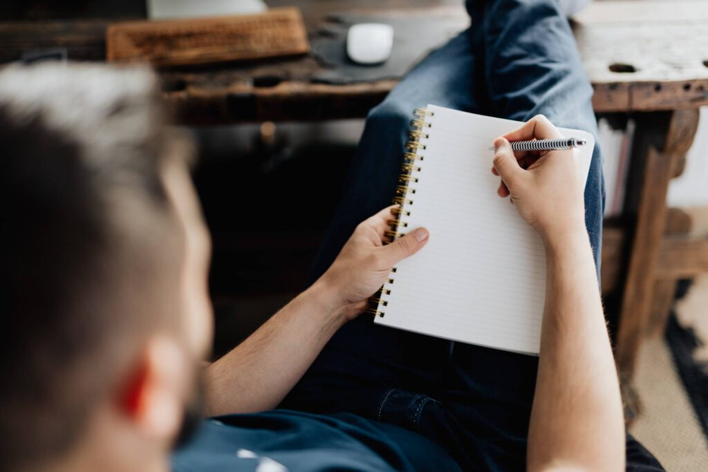 Man Relaxing in His Home Office and Writing in a Diary Free Photo