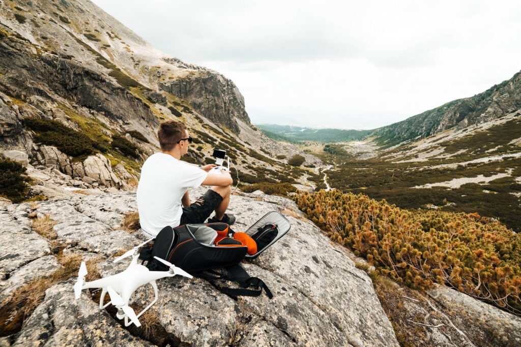 Man Setting Up a Drone for Aerial Photography in Mountains Free Photo