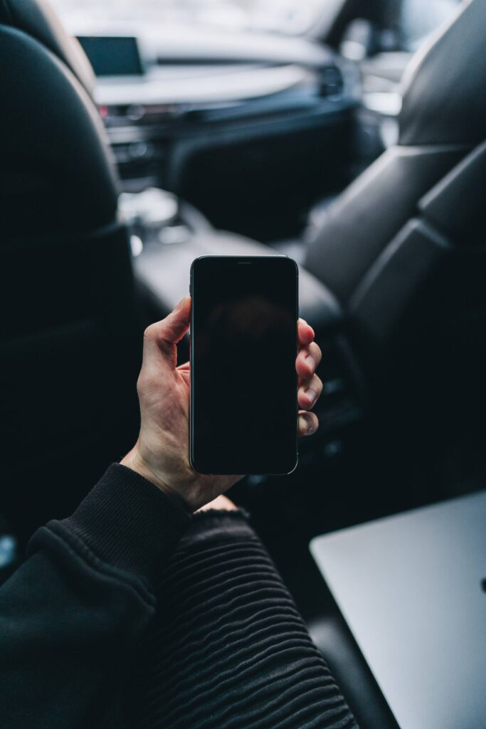 Man Sitting in a Car and Holding an iPhone Free Photo