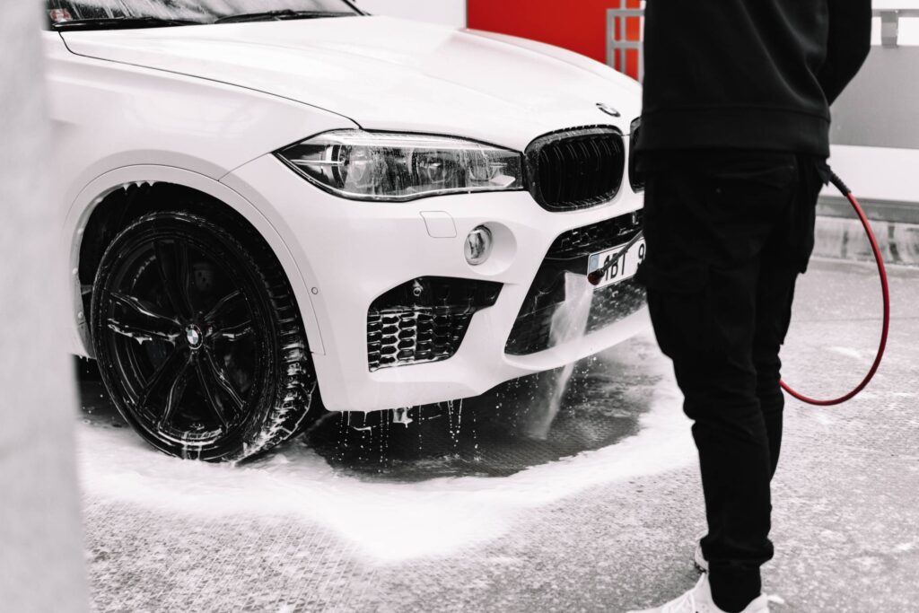 Man Washing White Car in a Self-Service Car Wash Free Photo