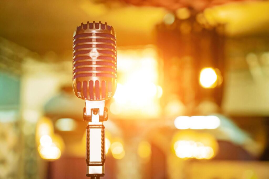 Microphone on stage at outdoor night party, abstract bokeh light background. Close up. Stock Free