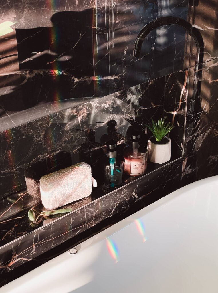 Modern Black Glossy Marble Bathroom Detail with Shampoos and Shower Sponge Free Photo