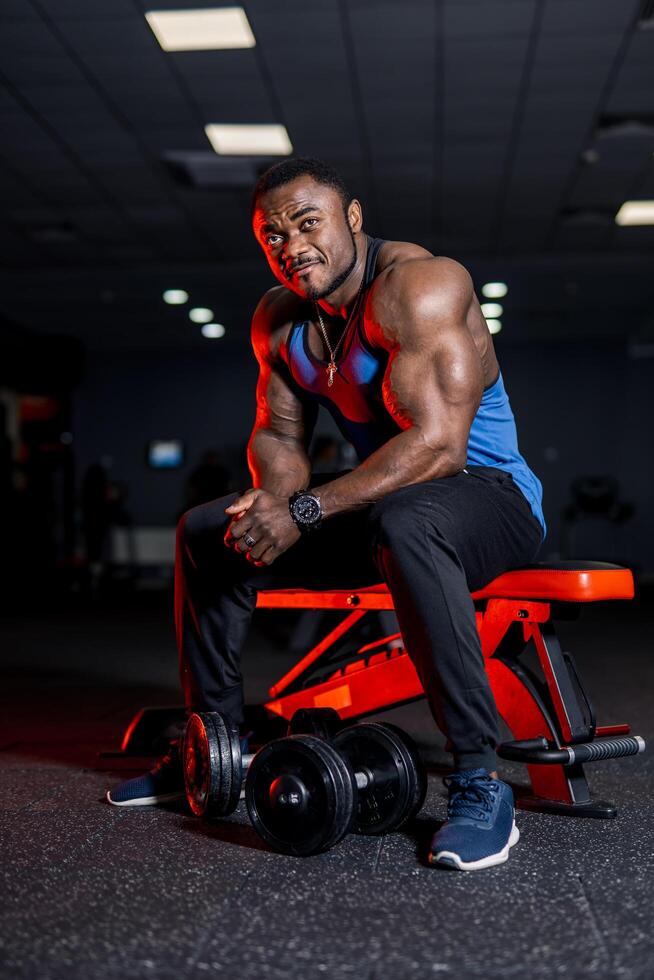 Muscular afro american sports man looking at camera over black gym background. Perfect muscular body with strong muscles. Stock Free