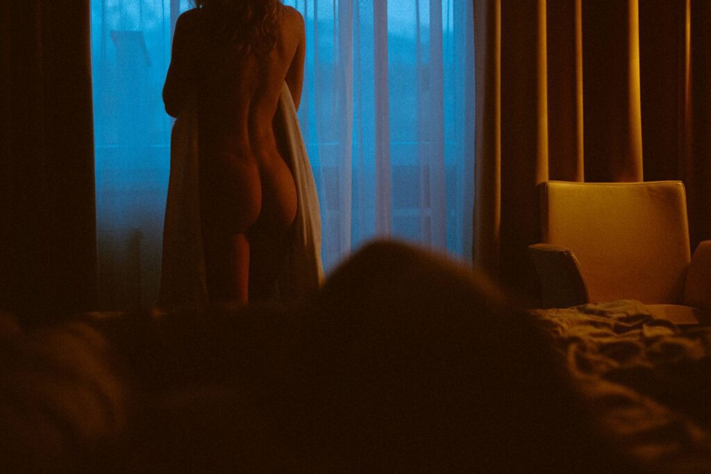 Naked Woman Standing by Window in Dark Hotel Room in The Evening Free Photo