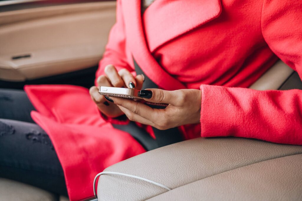 Nicely Dressed Woman Using Her Phone in a Car Free Photo