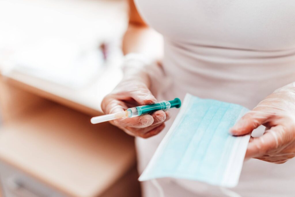 Nurse Holding a Syringe and Face Mask Free Photo