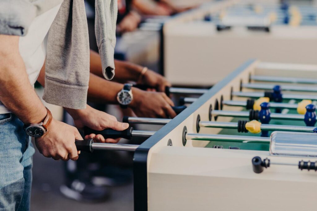 People, lifestyle, gambling and recreation concept. Active male player enjoy spare time while play table football together. People have kicker match Stock Free