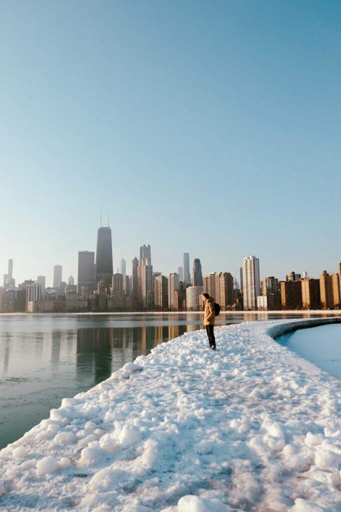 a person standing in the snow near a body of water