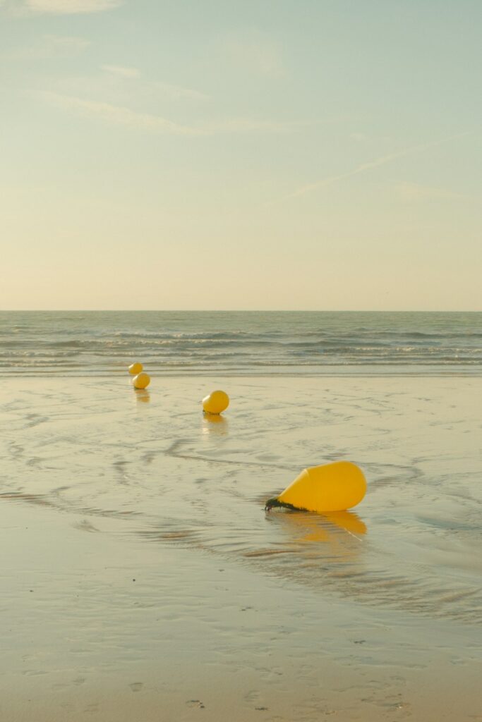 a group of yellow buoys floating on top of a sandy beach