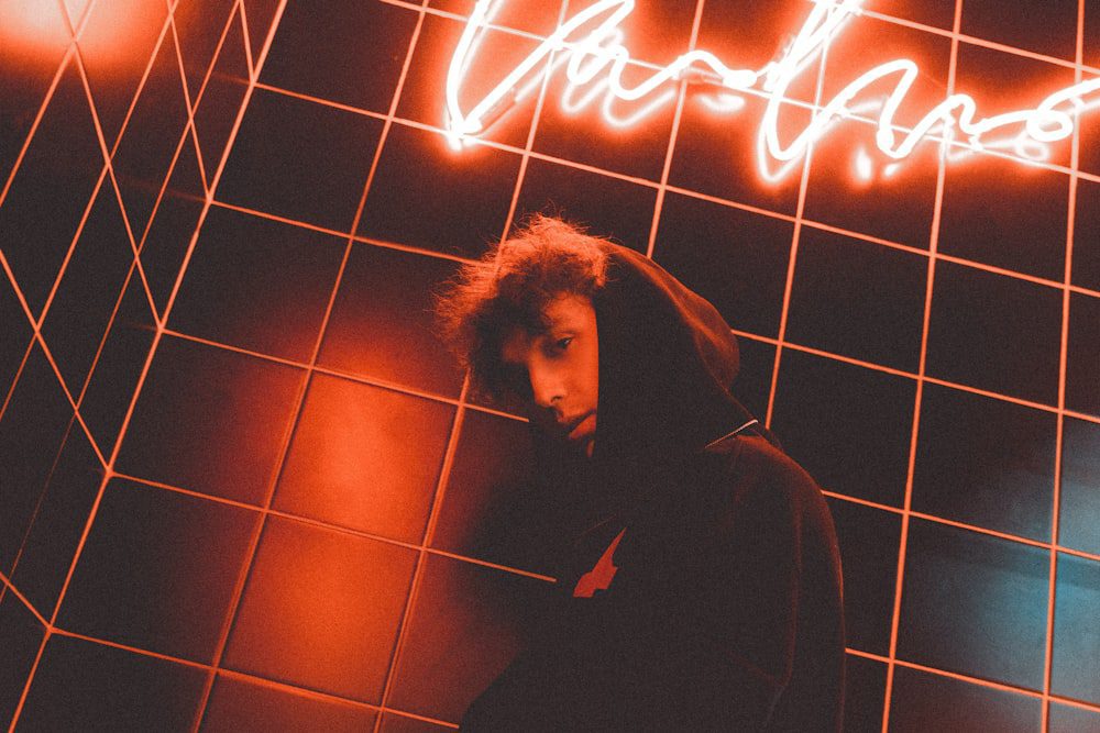 a man standing in front of a neon sign