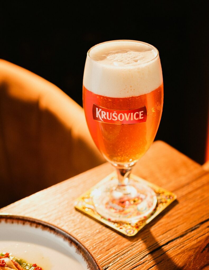 a glass of beer sitting on top of a wooden table