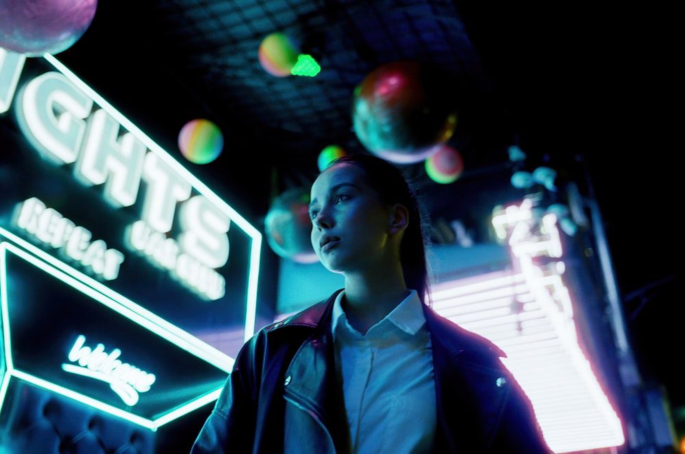 a woman standing in front of a neon sign