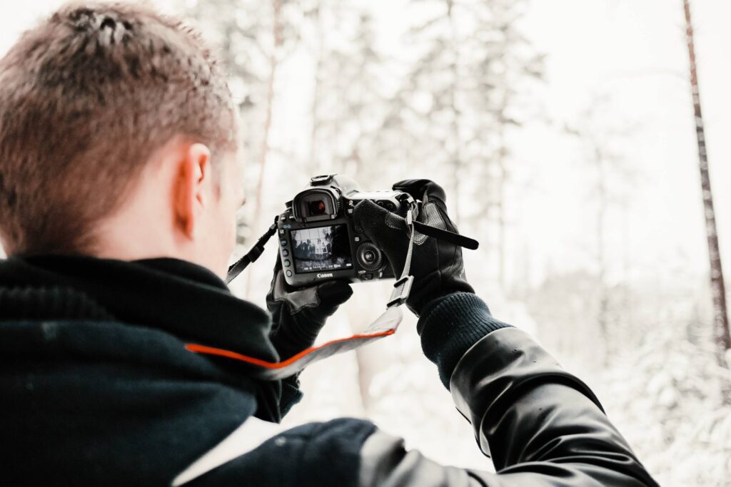 Photographer in Snowy Forest Taking Winter Photos Free Photo